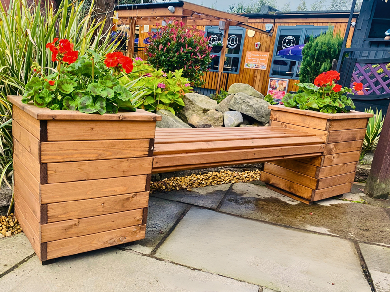 A wooden bench with two gaps for plants each side.
