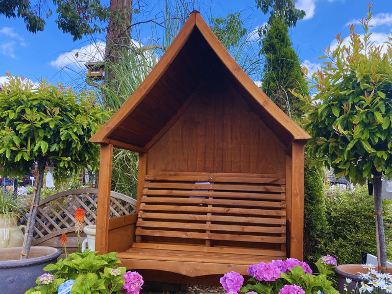 A wooden arbour with a sloped roof. 