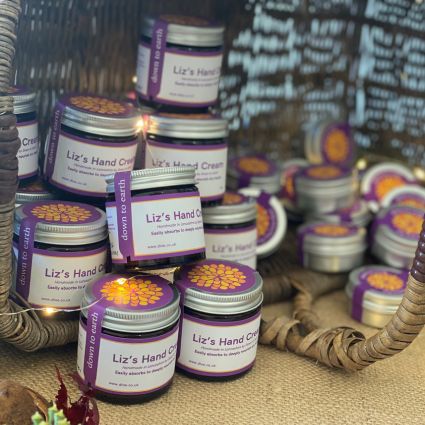 A selection of handmade lipbalms and body butters in a wicker basket.